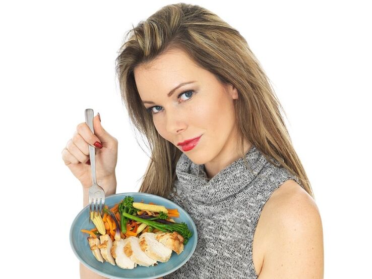 девушка ест курицу с овощами, чтобы похудеть